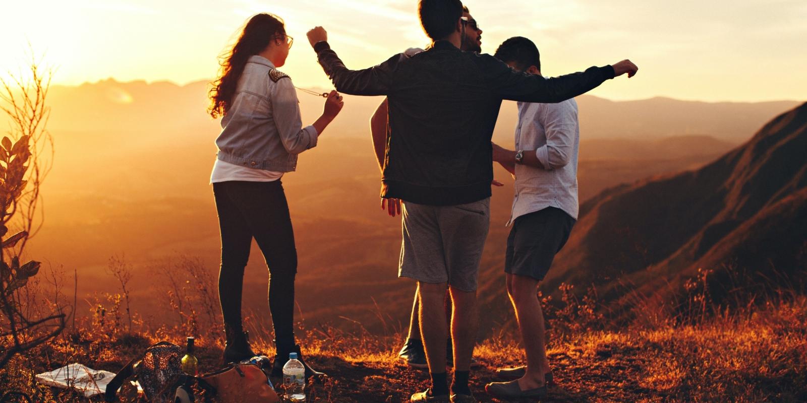 Four People Standing at Top of Grassy Mountain
